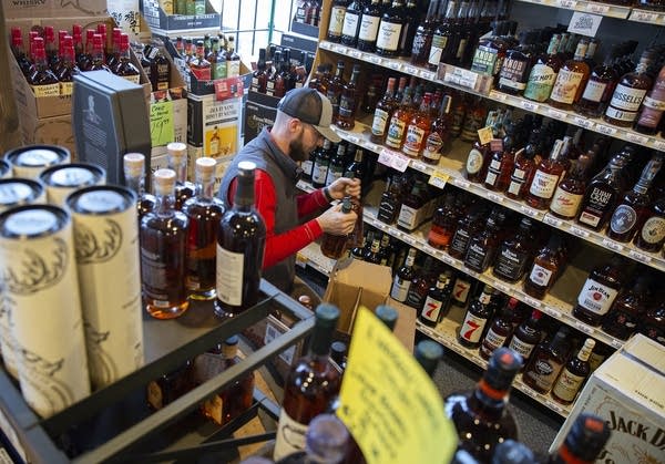 A man places bottles on shelves.